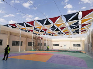 Colorful tensile sail shade installation in dubai school courtyard
